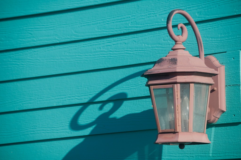 Lamp on turquoise building casting shadow